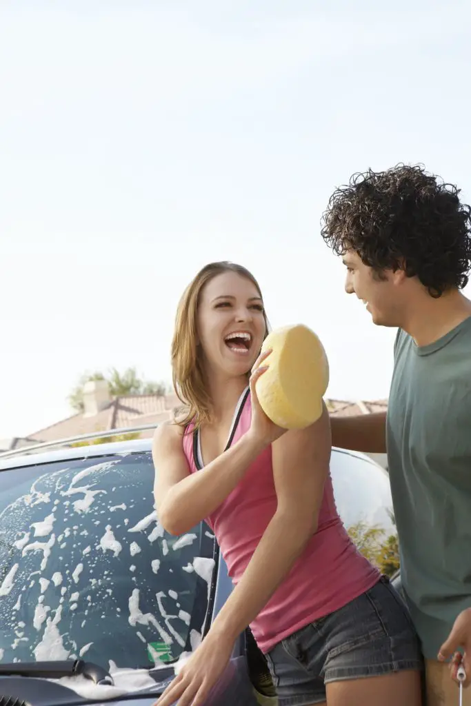 Young couple washing car outdoors